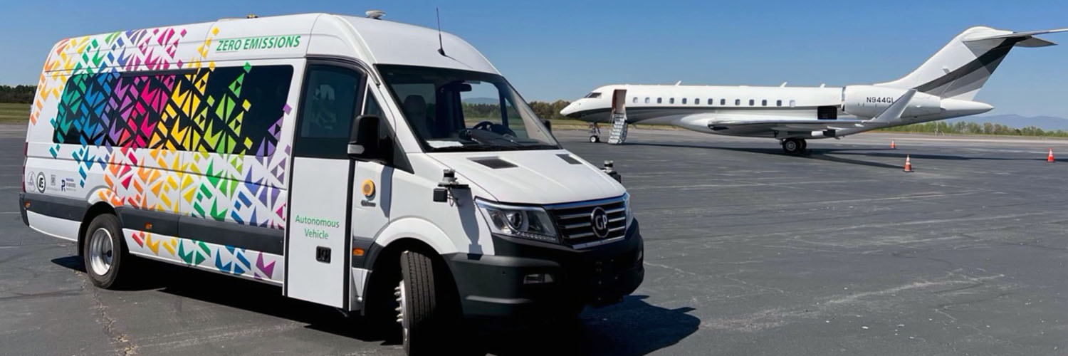 Autonomous Shuttle On The Tarmac, With A Jet In The Background